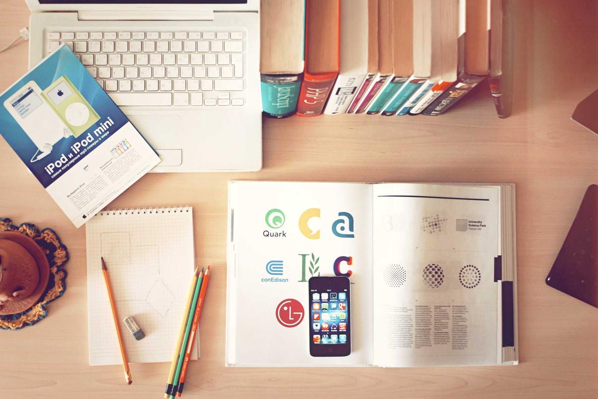 A desk with a smartphone, notebook and books